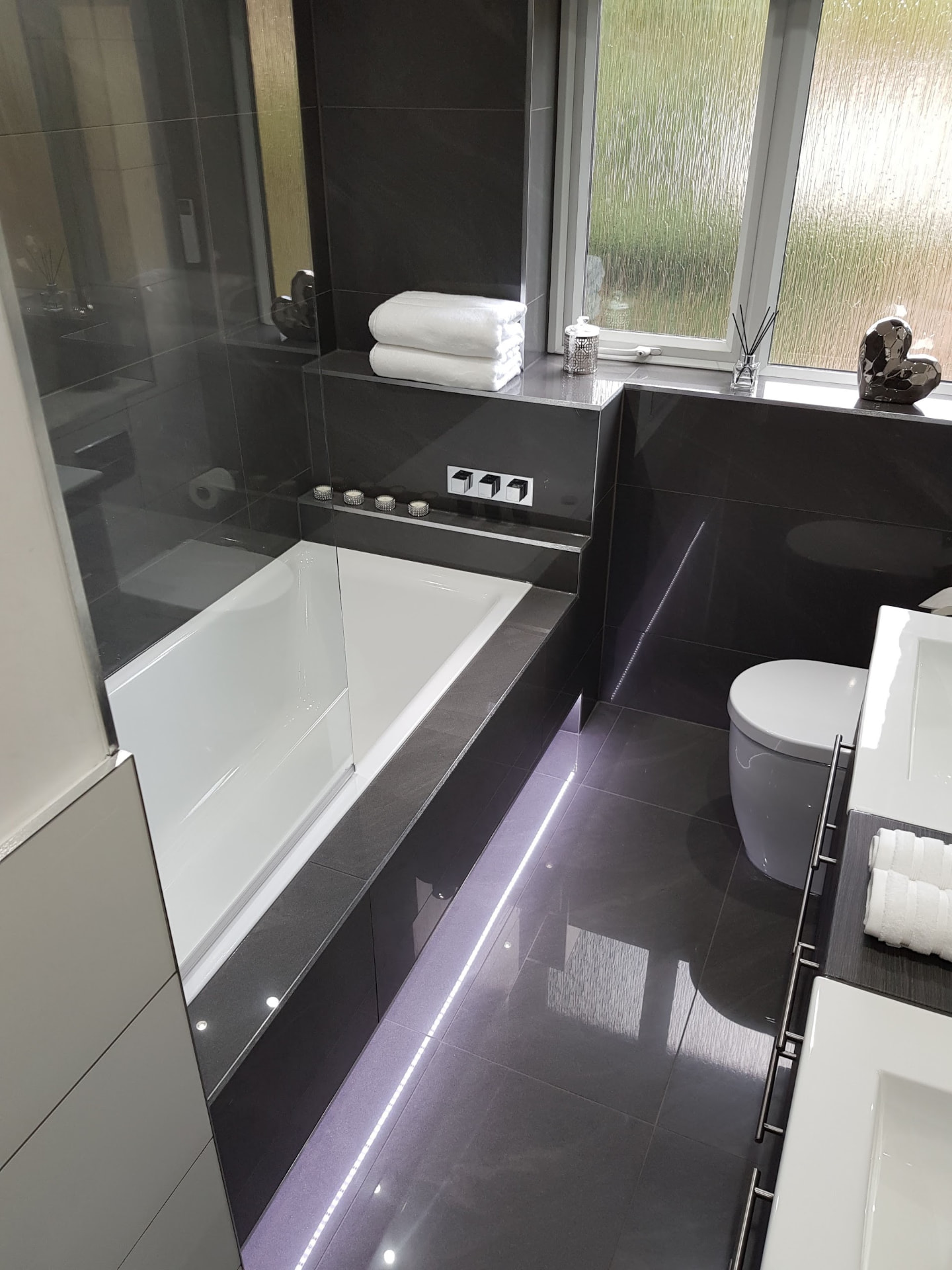 Alt angle of the black bathroom suite with LED plinth strip & chrome ladder rail in Leamington Spa