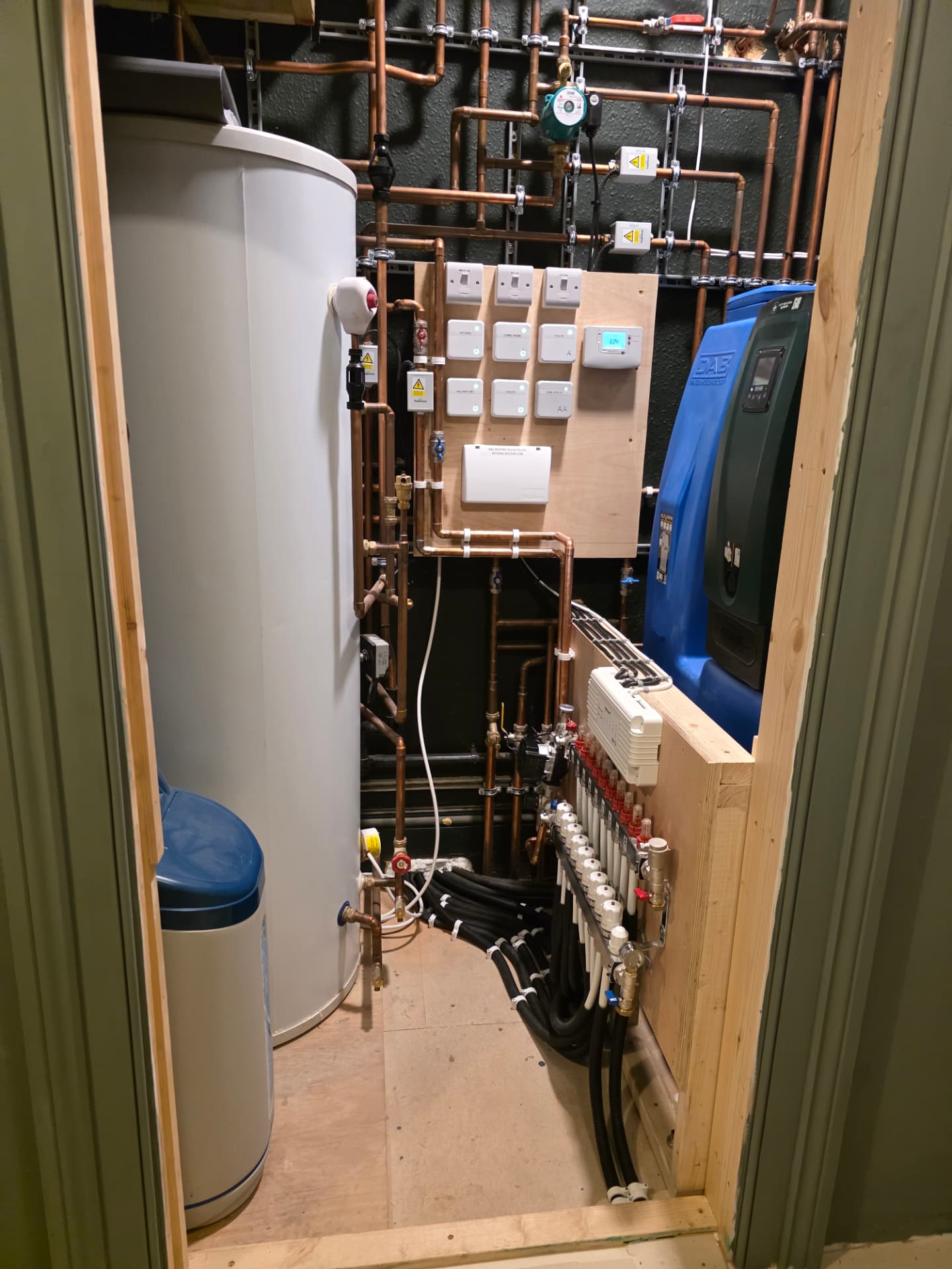 Plant-room door view: cylinder, softener, zone controls & UFH manifold
