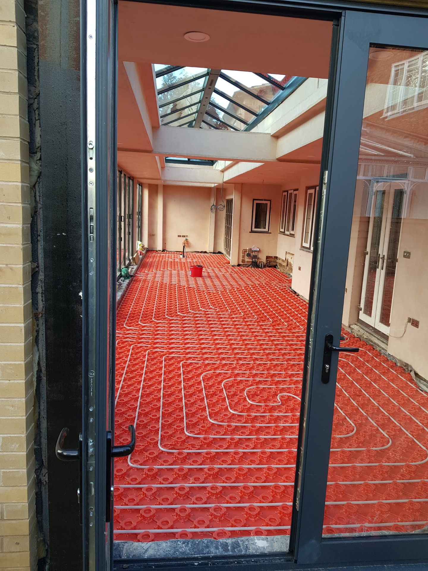 Red egg-shell clip-rail UFH pipework snaked across a full orangery build