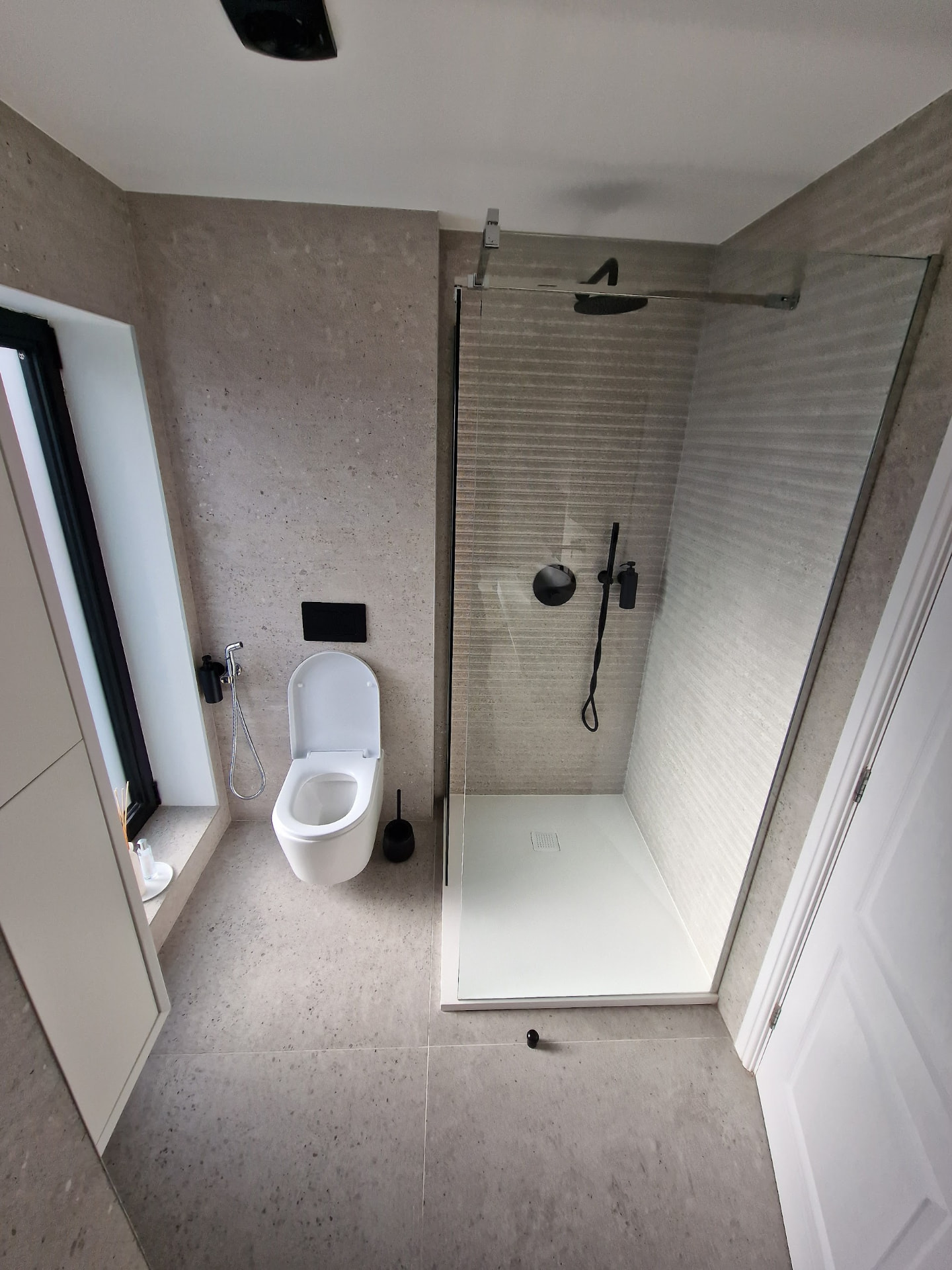 Minimalist wet room with matte-black fittings & ribbed stone shower wall