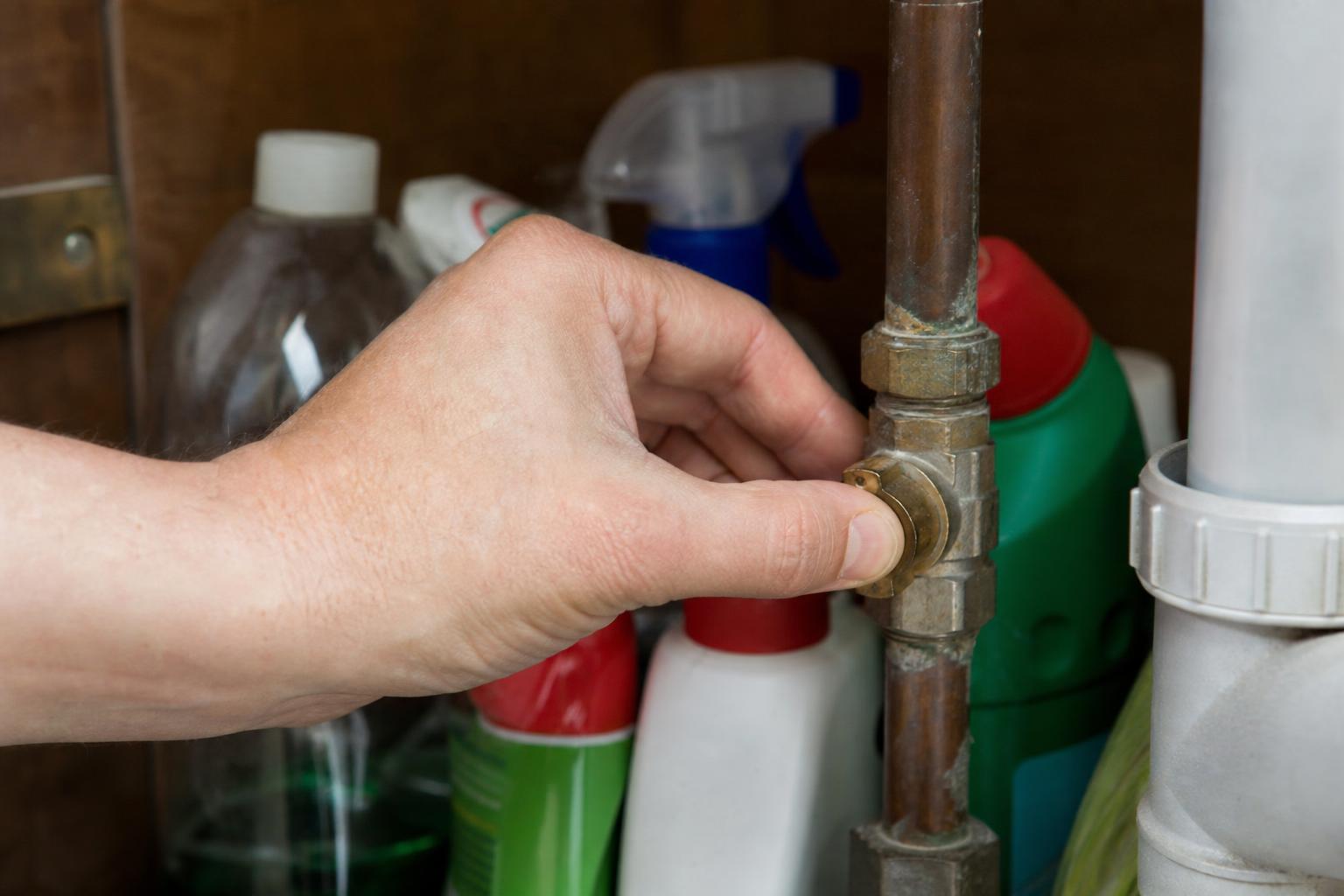 Turning off the internal stopcock under a kitchen sink to stop a leak